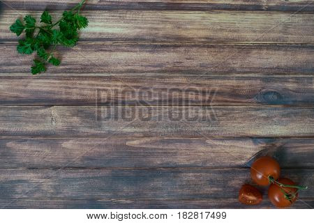 Vegetarian ingredients on wooden texture background with copy space. Top view of parsley tomato.