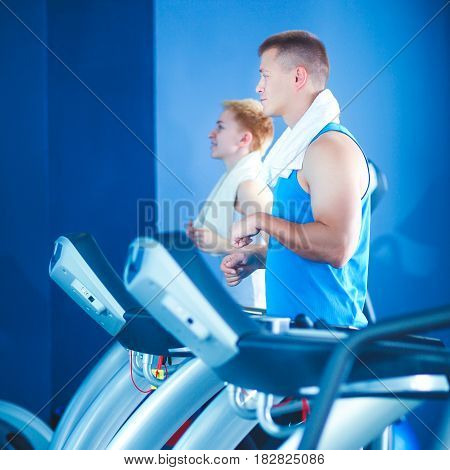 Group of people at the gym exercising on cross trainers .