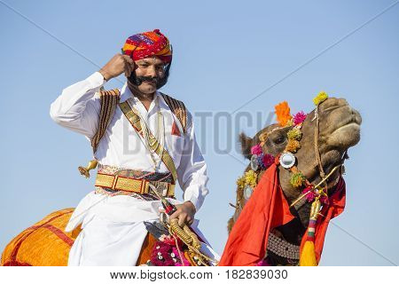 JAISALMER INDIA - FEBRUARY 09 2017 : Camel and indian men wearing traditional Rajasthani dress participate in Mr. Desert contest as part of Desert Festival in Jaisalmer Rajasthan India