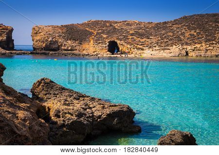Comino Malta - Beautiful azure sea water at the famous Bluw Lagoon of Comino with snorkeling tourists enjoying the summer sunshine