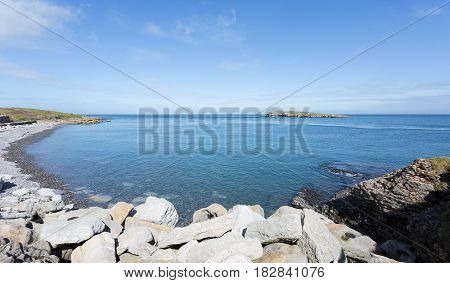 Rocky coastline at Moelfre Anglesey in North Wales with distant view of Moelfre Island (Ynys Moelfre)