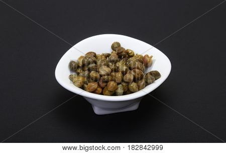 bowl with fresh capers isolated on black background