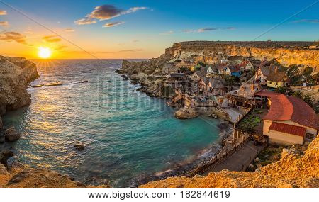 Il-Mellieha Malta - Panoramic view of the famous Popeye Village at Anchor Bay at sunset