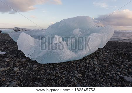 Ice breaking from glacier over black rock beach Iceland winter season natural landscape