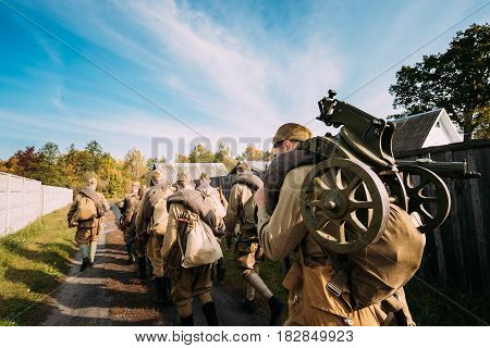 Group Of Re-enactors Dressed As Soviet Russian Red Army Infantry Soldiers Of World War II Marching Walking Along Country Road In Russian Village At Autumn Season.