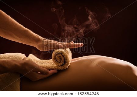 A professional therapist applies a hot towel on the back of a man. Hot towel compress. SPA treatment