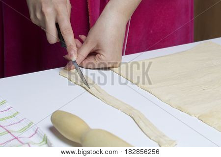 Stages Of Preparation Of Meat Glomeruli. A Woman Slices Thin Strips Of Dough. Next To The Table Is A