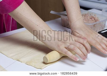 Stages Of Preparation Of Meat Glomeruli. A Woman Rolls Out The Dough. Next To The Table Is A Stuffin