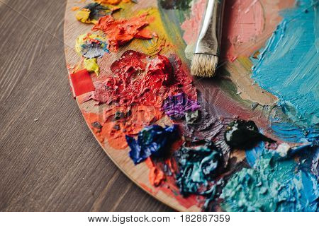 color palette with fresh paint and brush on wood table