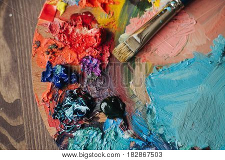 color palette with fresh paint and brush on wood table