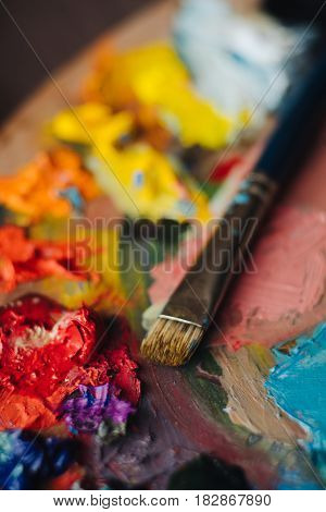 color palette with fresh paint and brush on wood table