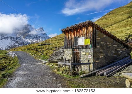 A Mountain Wooden Hut beside the road to Bachsee Switzerland in autumn with yellow grass snow and blue sky