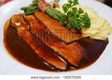 Delicious grilled beef tenderloin with red wine sauce serve with potato vegetable and beacon