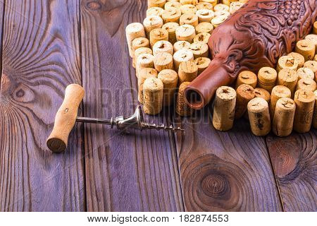 Clay bottle metal corkscrew and cork on a wooden table
