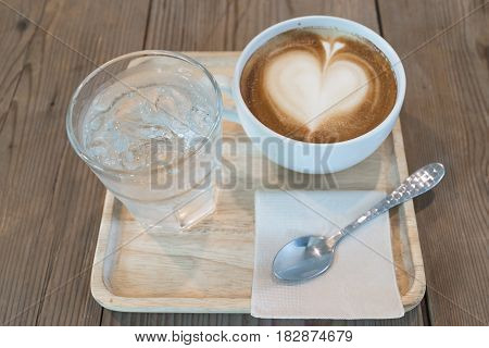 view of hot cappuccino coffee with ice water on wood table