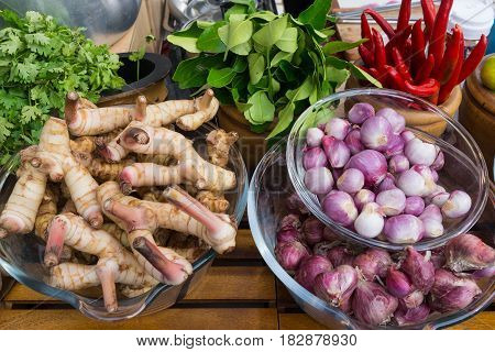 Tom Yam Kung ingredients red onions chili galangal kaffir lime parsley on wood table