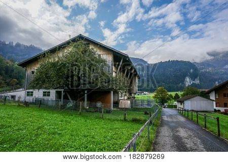 Switzerland - October 15 2016: View of barn with green trees front yard grass beside the road Lungern Switzerland