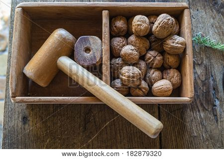 Top view of traditional wooden hammer beats walnuts on the wooden table