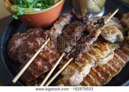 Closed up of mixed grilled meat and skewers on wooden sticks tasty pork lamb and chicken with vegetables