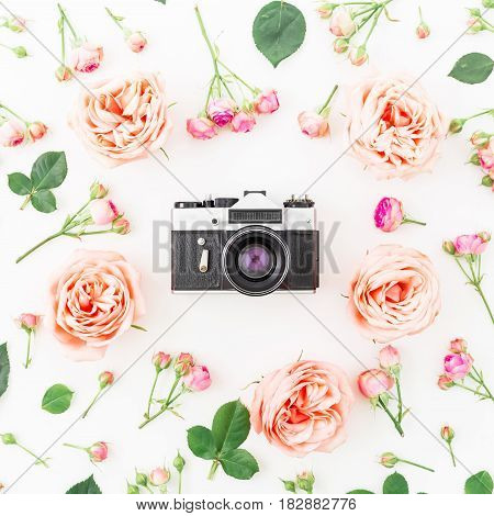 Round frame with pink roses and Old retro camera on white background. Flat lay, top view. Floral background.