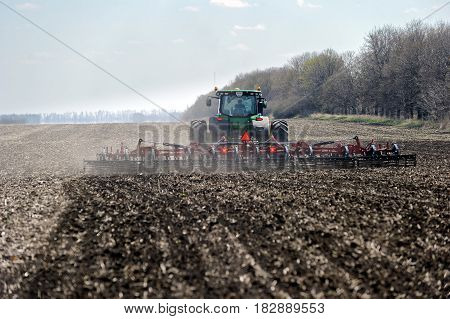 Kharkiv Ukraine - April 13 2017: Tractor with trailed planter working in field in a sunny spring day in Kharkiv Oblast Ukraine on April 13 2017