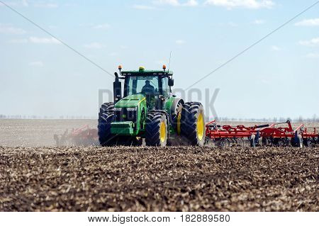 Kharkiv Ukraine - April 13 2017: Tractor with trailed planter working in field in a sunny spring day in Kharkiv Oblast Ukraine on April 13 2017