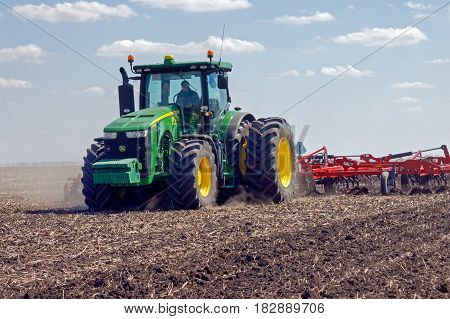 Kharkiv Ukraine - April 13 2017: Tractor with trailed planter working in field in a sunny spring day in Kharkiv Oblast Ukraine on April 13 2017