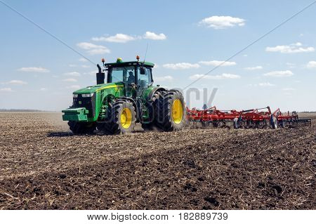 Kharkiv Ukraine - April 13 2017: Tractor with trailed planter working in field in a sunny spring day in Kharkiv Oblast Ukraine on April 13 2017
