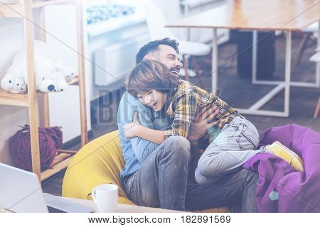 I love you, daddy. Riant pre-adolescent boy rushing into father's arms while having fun on colorful hammocks