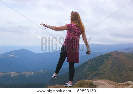 Girl standing on edge of mountain, enjoying the beautiful sunset at Carpathians
