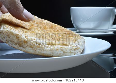 Hand is picking whole grain bread on a white plate.