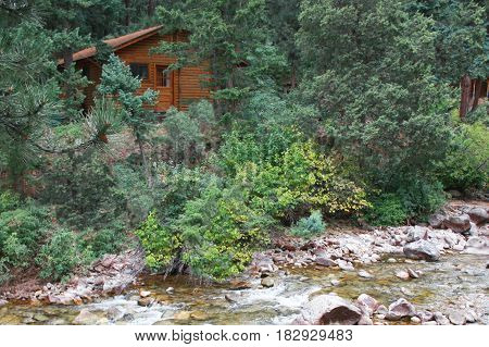 Log cabin tucked into mountainside near rocky stream