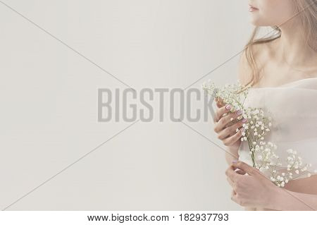 Lovely girl in white lingerie. Sensual photo. She holds white spring flowers near her breast. Man is unrecognizable. Close-up