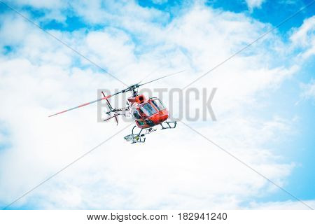 red helicopter in front of an overcast sky
