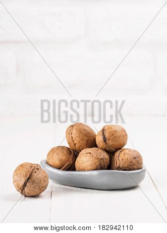 View on inshell walnut on white wooden background with copy space. Vertical.