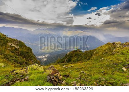 Beautiful view on mountains with hanging bridge and green grass on foreground