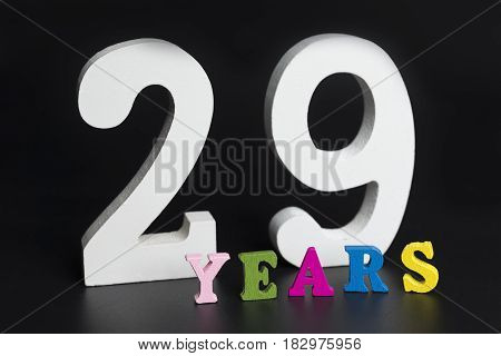 Letters and numbers twenty-nine years on a black isolated background.