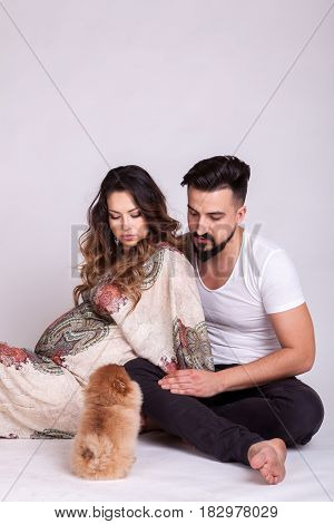 Happu pregnant woman with her husband and dog in studio photo. Wife and husband. Parenthood and expecting baby