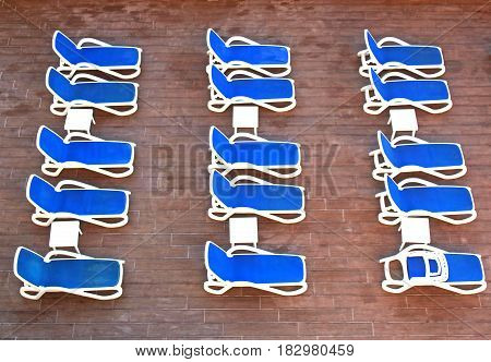 rows of blue deckchairs at a hotel swimming pool, waiting for guests