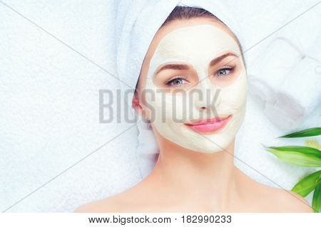 Spa Woman applying Facial clay Mask. Beauty Treatments. Close-up portrait of beautiful girl with a towel on her head applying facial mask.