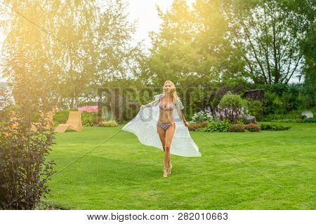Youmg Beautiful Blond Woman In Beautiful Summer Garden Is Barefoot On Lawn