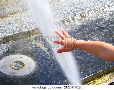 Baby Hand In Fontain, Children Near A Splashing Fontain