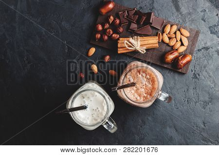 Banana And Chocolate Smoothie In Two Jars, Protein Milkshake, Nuts, Chocolate Cubes, Dates, Cinnamon