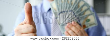 Man In Suit And Hold Thumbs Up Pack Of Hundred Dollar Bills Closeup. Stock Market Financial Illegal 