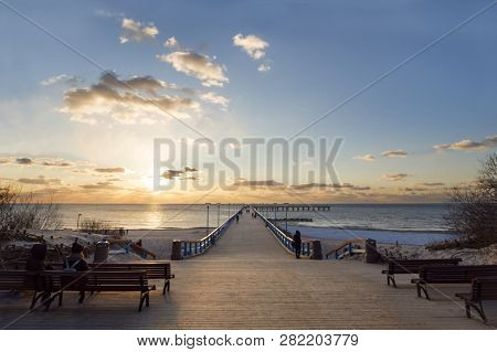 Sunset And Vacationers On The Bridge Of Palanga On The Baltic Sea In Klaipeda, Lithuania