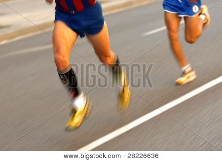 Maratonský běžec nohy na silnici následuje další běžec s rýžováním rozostření