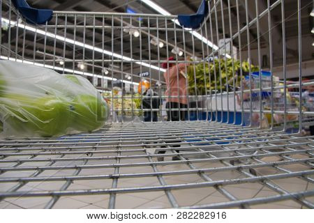 View From Shopping Cart Trolley Basket At Supermarket Self-service Grocery Shop. Retail. Blurred Bac