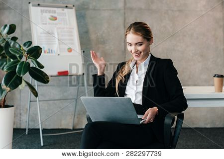 Smiling Businesswoman Looking At Laptop And Throws Up Hands