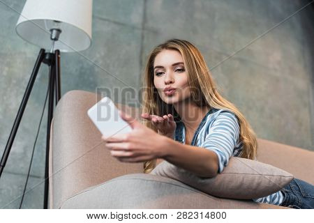 Adult Girl Lying On Pink Sofa And Taking Selfie On Smartphone
