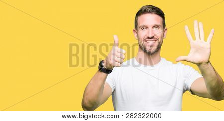 Handsome man wearing casual white t-shirt showing and pointing up with fingers number six while smiling confident and happy.